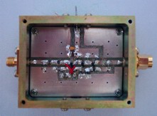 [Photograph of box with connector, feedthrough capacitor and blanking plate]